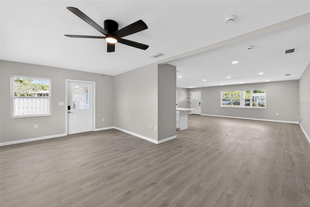 An open-concept living area features light wood-look flooring, gray walls, and a black ceiling fan — 6224 7TH AVENUE DRIVE W, BRADENTON, FL