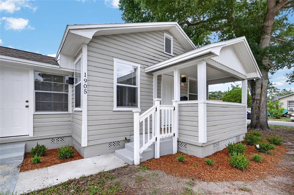 A gray house with white trim features a covered front porch and a small staircase — 1905 24TH STREET S, ST PETERSBURG, FL