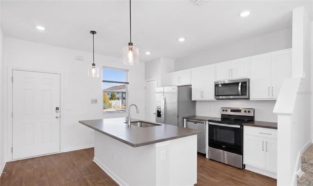 A kitchen with a center island, stainless steel appliances, and white cabinets on wood flooring — 57 ELMHURST LANE, ST AUGUSTINE, FL