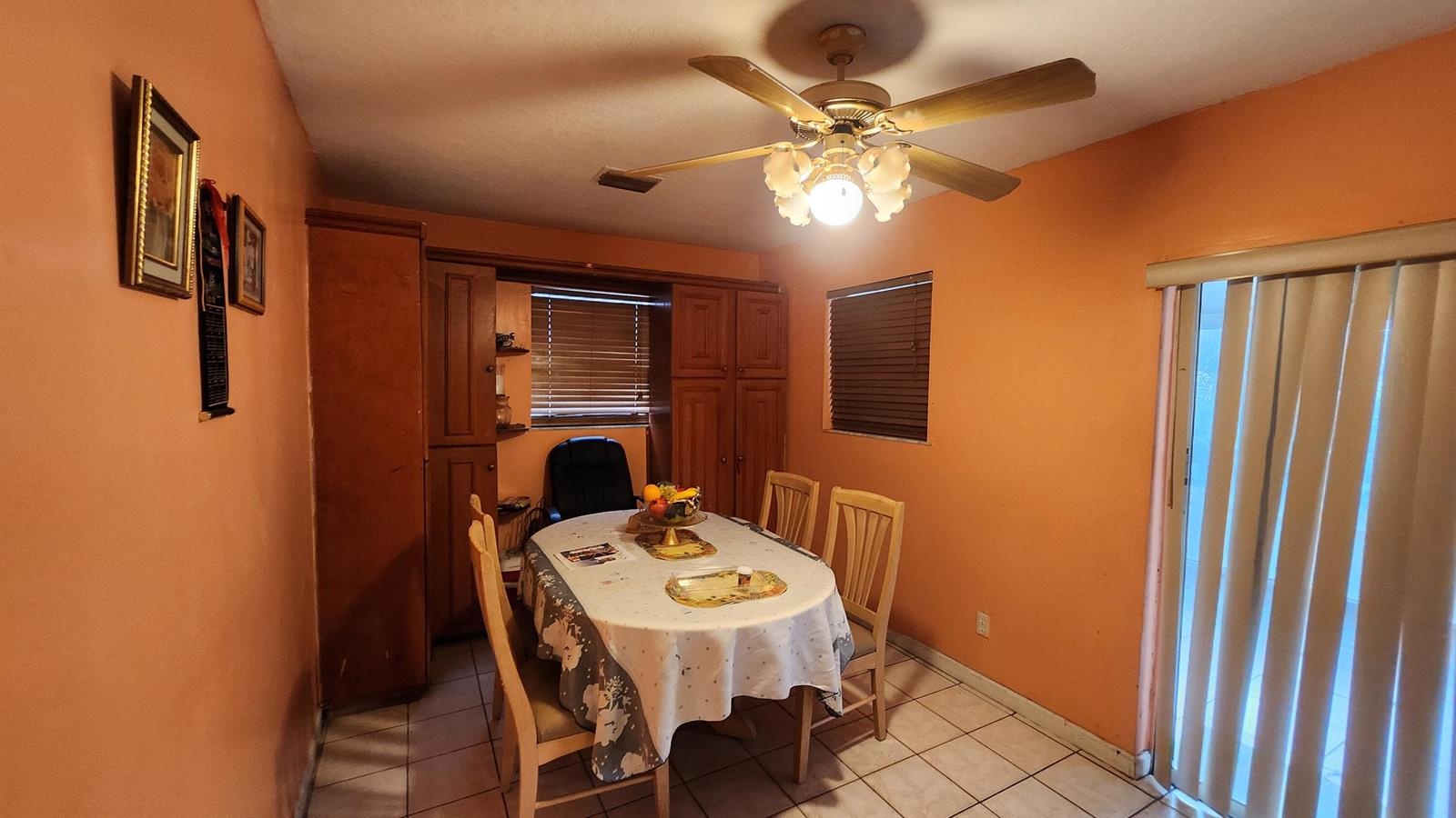 A dining room with orange walls, a ceiling fan, a table, and tiled flooring — 1207 Hatteras Circle, FL 33413, FL