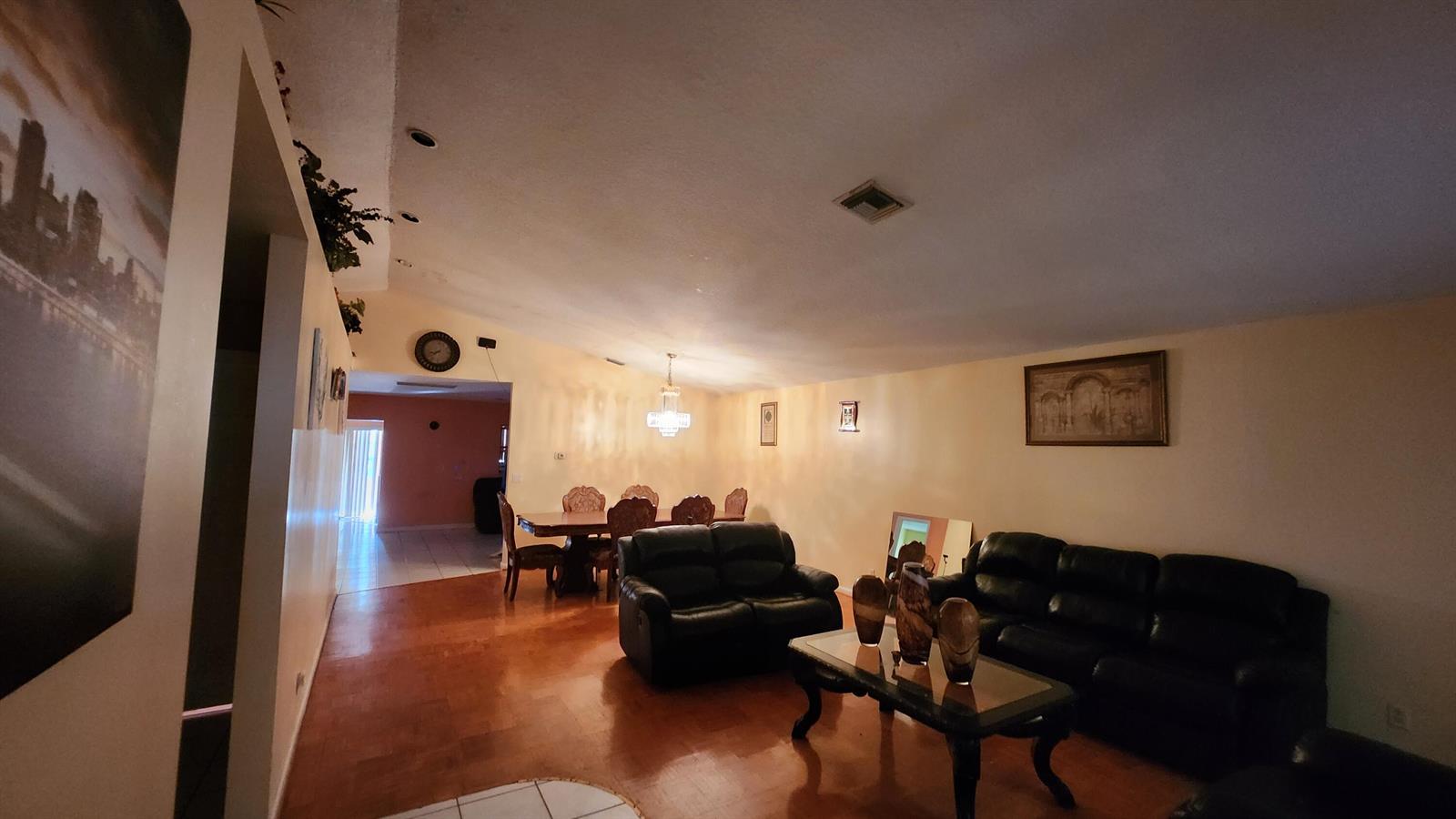 A living room and dining area with dark leather furniture, wood flooring, and a chandelier — 1207 Hatteras Circle, FL 33413, FL