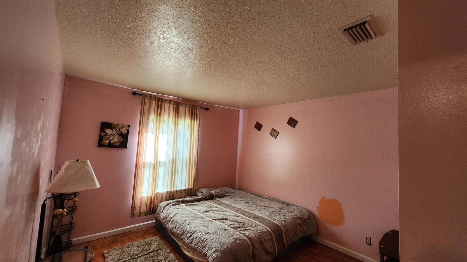 A bedroom with pink walls, a bed, a window with curtains, and a floor lamp — 1207 Hatteras Circle, FL 33413, FL
