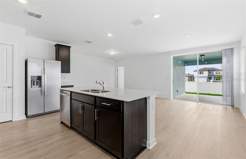 A kitchen with a dark island, stainless steel appliances, and a sliding door to a patio — 6913 SW 90TH LANE, OCALA, FL