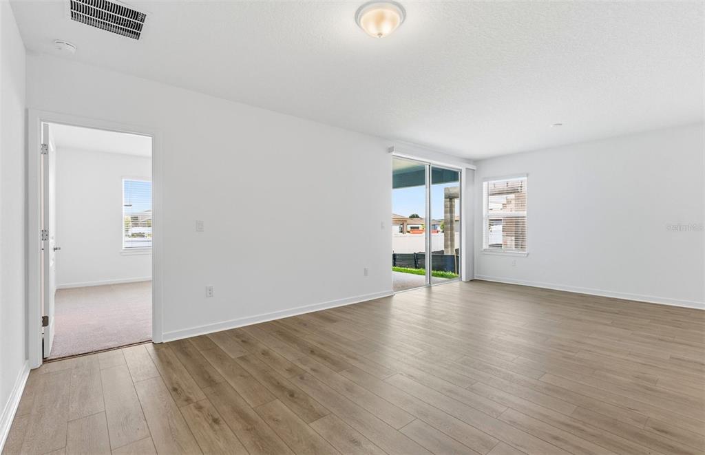 An empty room with light wood-look flooring, white walls, a sliding glass door, and doorway — 6913 SW 90TH LANE, OCALA, FL