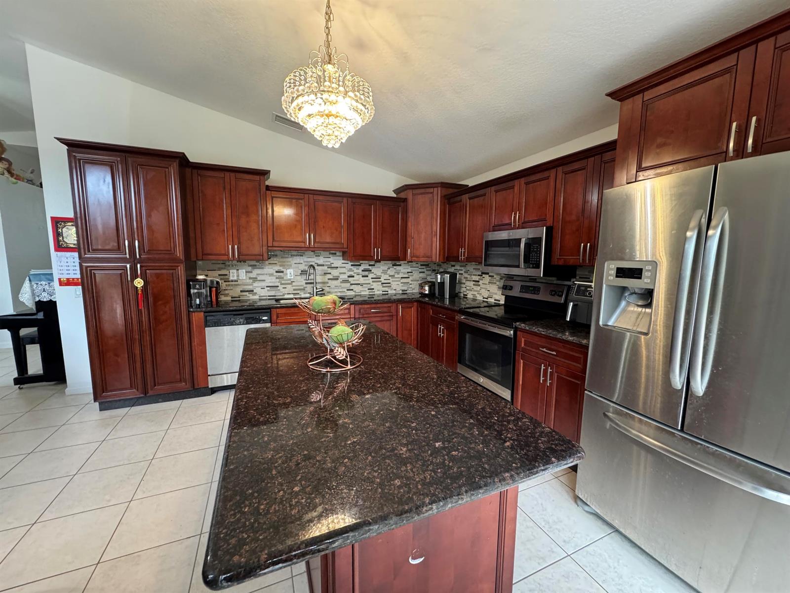 A kitchen features dark wood cabinets, granite countertops, a central island, and stainless steel appliances — 5076 Nautica Lake Circle, FL 33463, FL