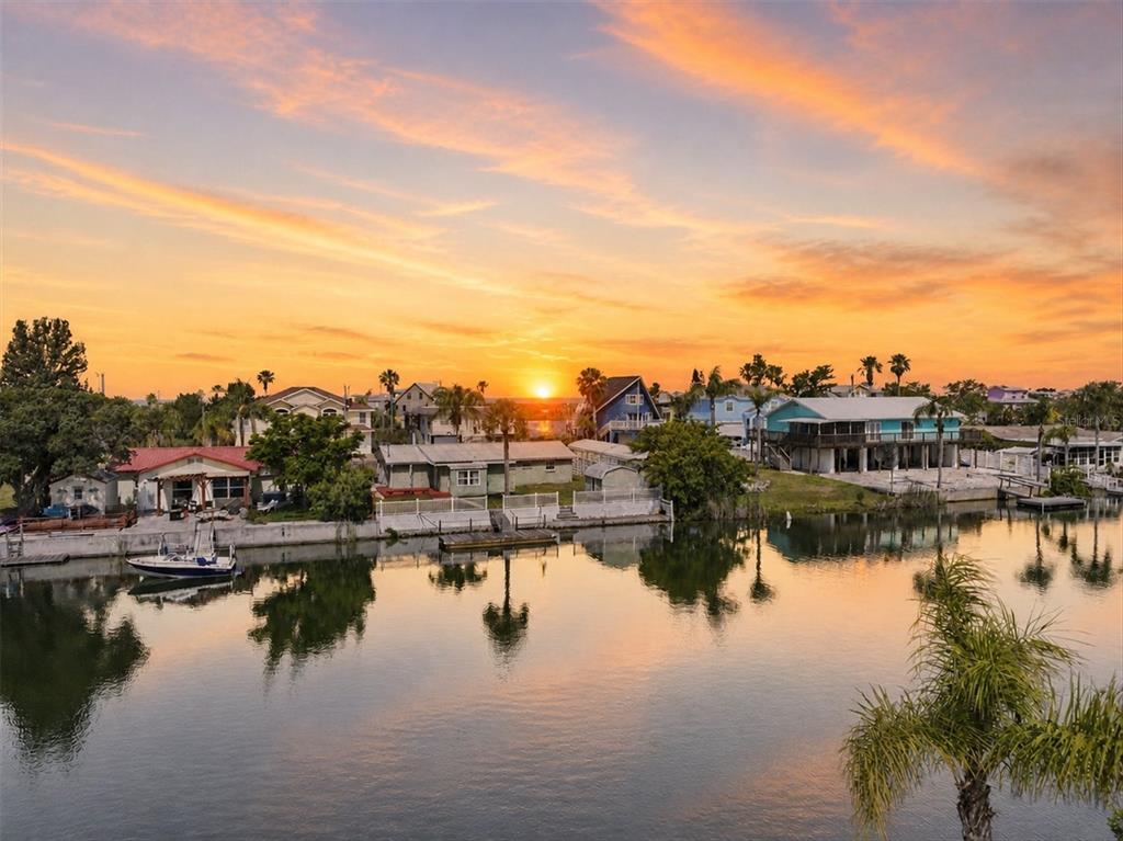 An aerial view of waterfront houses along a canal at sunset with a boat docked — 3347 OLEANDER DRIVE, HERNANDO BEACH, FL