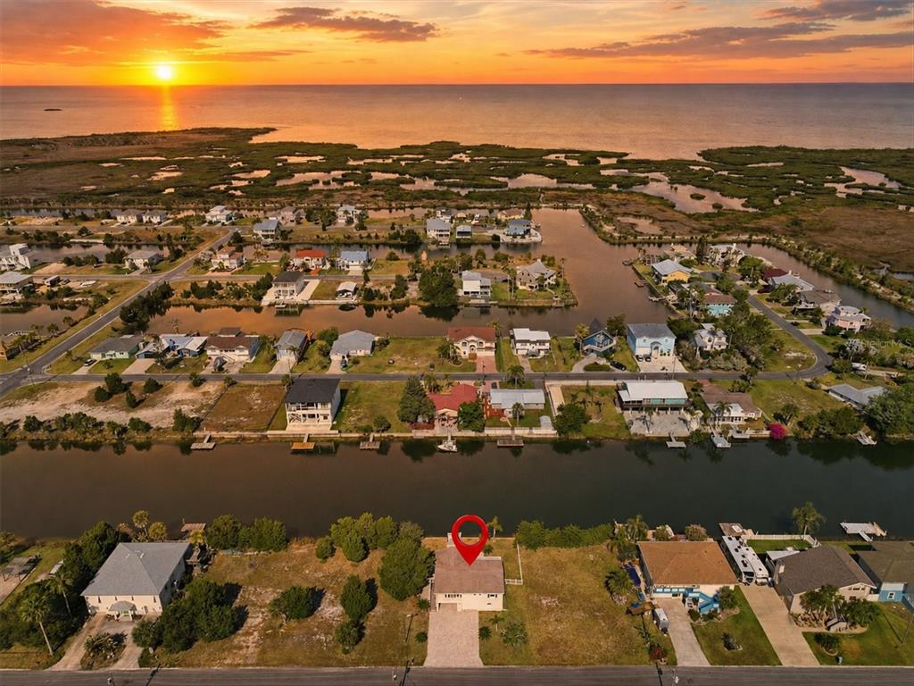 An aerial view shows a house with a red pin in a waterfront neighborhood at sunset — 3347 OLEANDER DRIVE, HERNANDO BEACH, FL