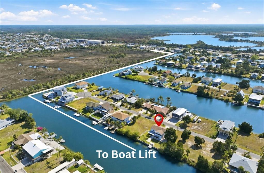 An aerial view shows a waterfront house with a boat lift on a canal — 3347 OLEANDER DRIVE, HERNANDO BEACH, FL