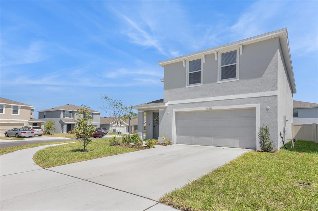 A two-story suburban house with a gray stucco exterior and a two-car garage — 37092 KINGS CROWN DRIVE, ZEPHYRHILLS, FL