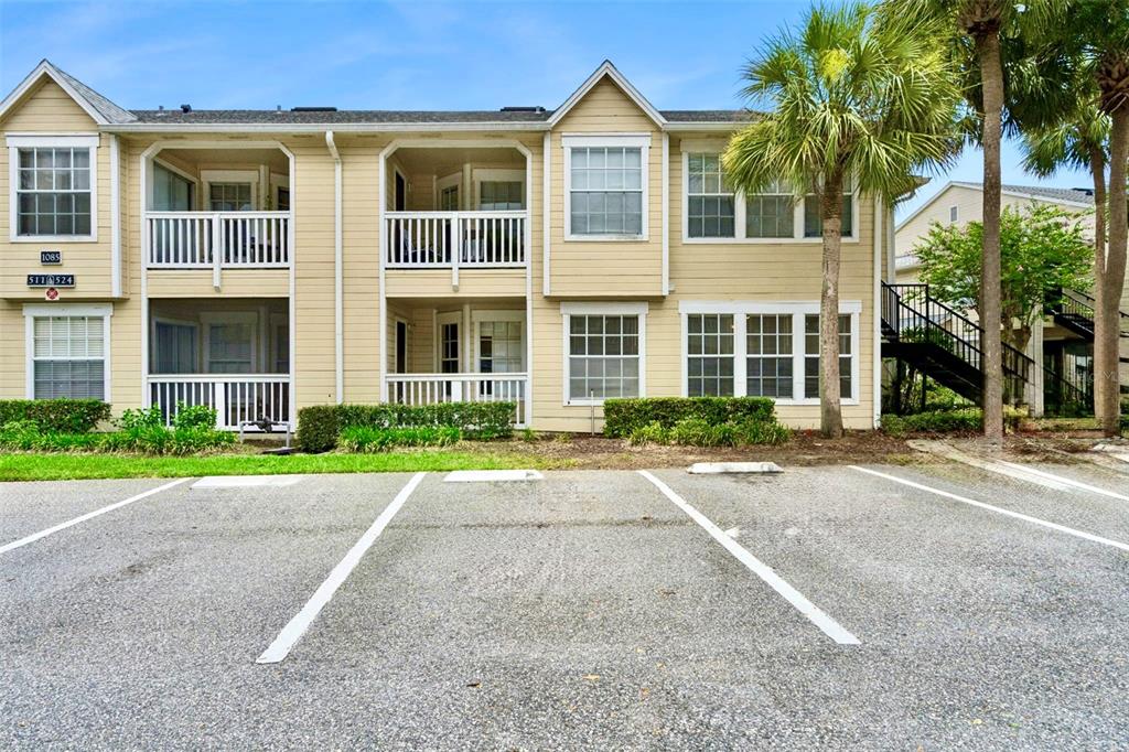 A two-story apartment building with tan siding, white railings, and a paved parking lot — 1085 S HIAWASSEE ROAD UNIT 513, ORLANDO, FL
