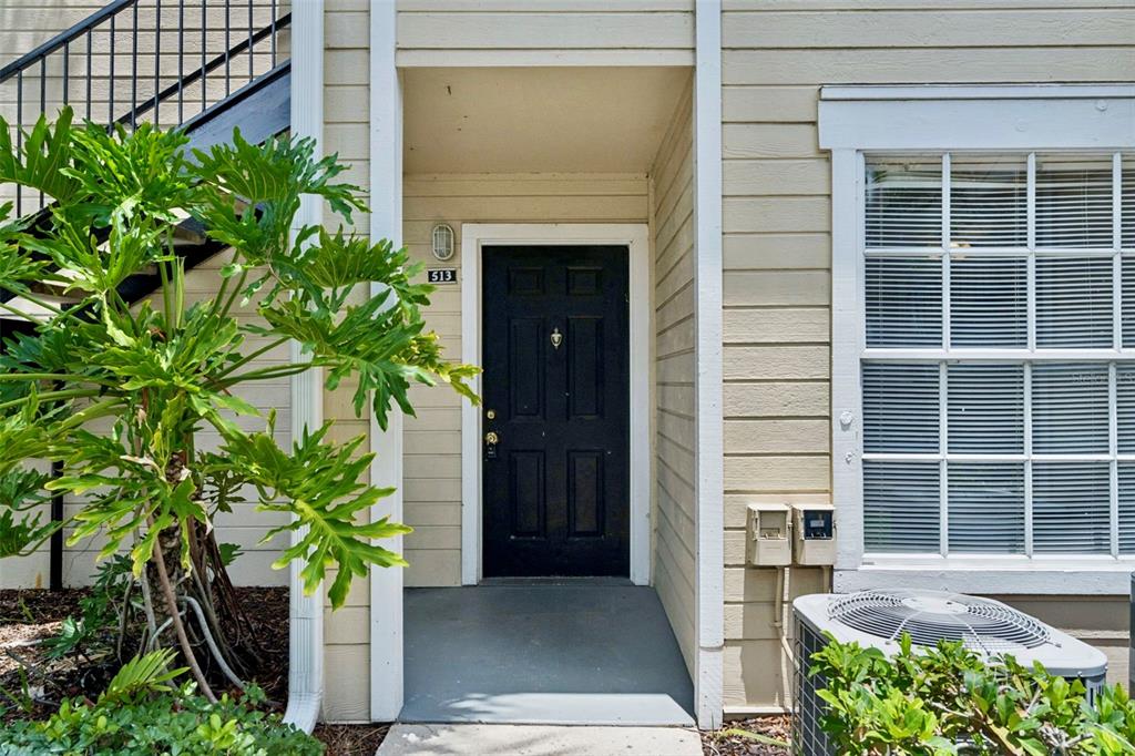 The exterior of a residential unit features a black front door numbered 513 — 1085 S HIAWASSEE ROAD UNIT 513, ORLANDO, FL