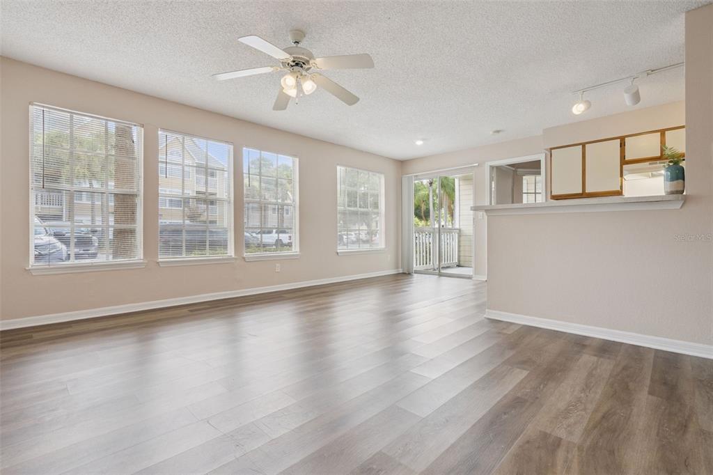 An empty living room with wood-look flooring, a ceiling fan, and large windows — 1085 S HIAWASSEE ROAD UNIT 513, ORLANDO, FL