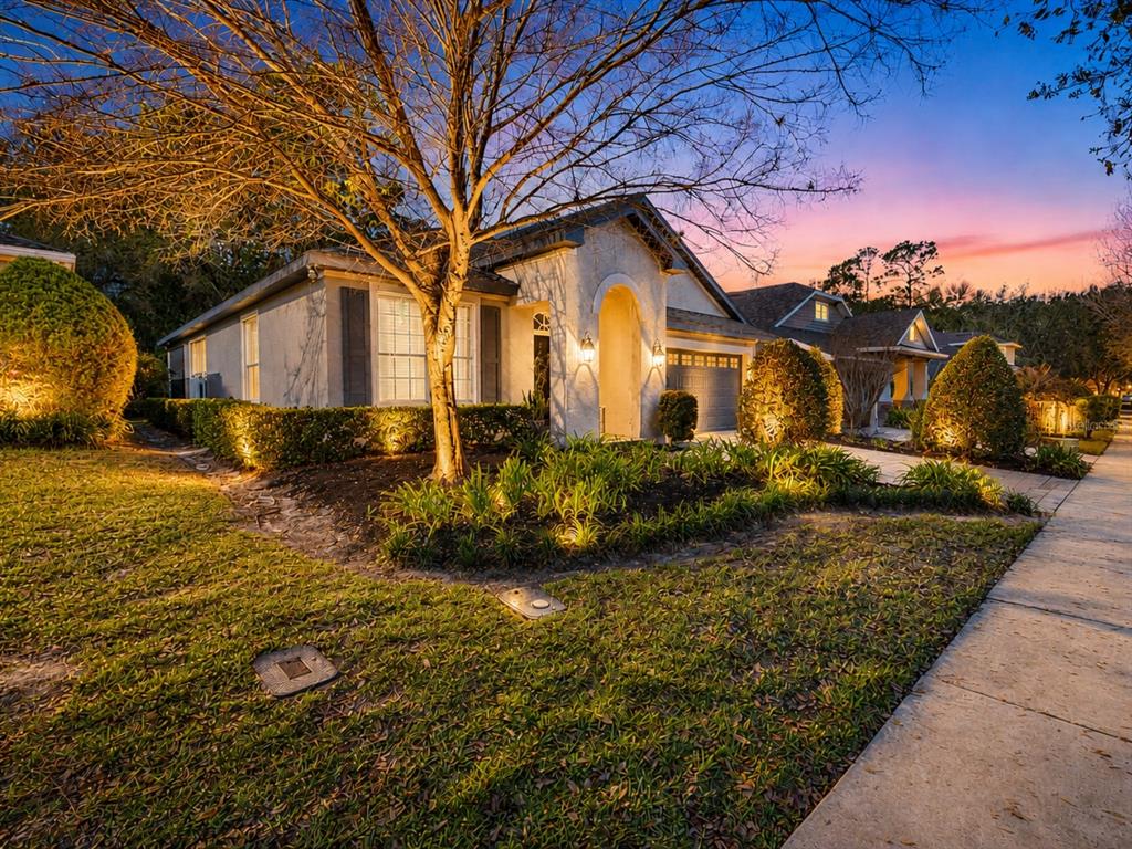A single-story house with a gray stucco exterior, arched entryway, and a paved driveway — 184 BIRCHMONT DRIVE, DELAND, FL