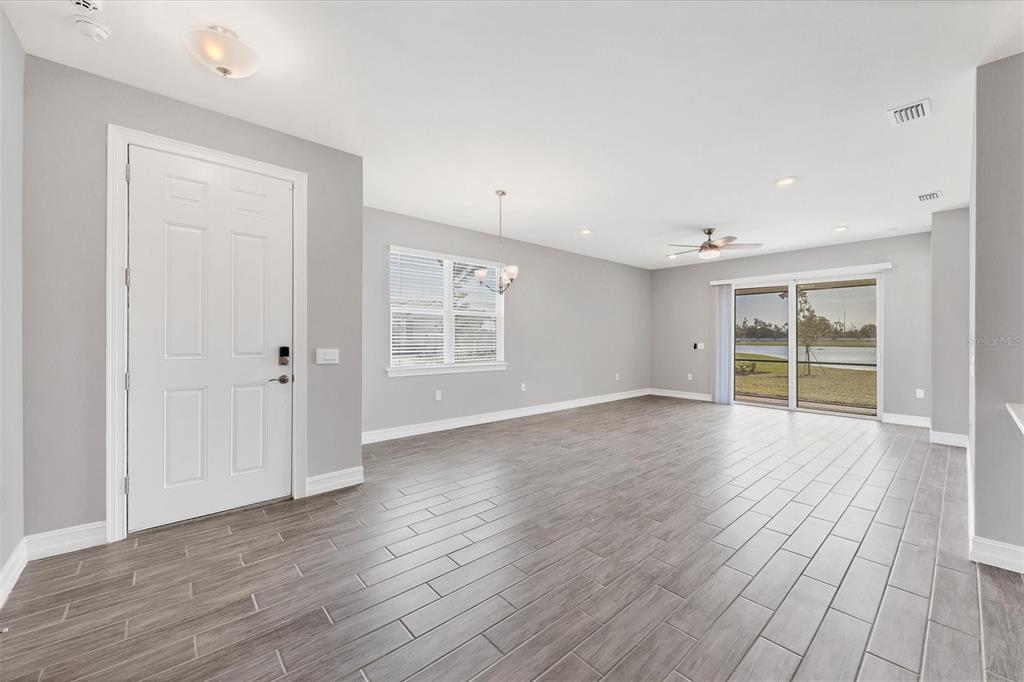 An open-concept living area features gray walls, wood-look tile flooring, and sliding glass patio doors — 111 IBIZA LOOP, VENICE, FL