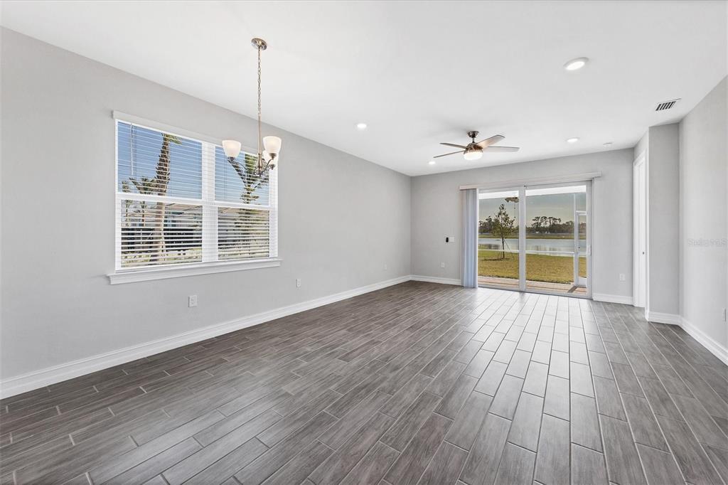 An empty room with gray wood-look tile flooring, a ceiling fan, and sliding glass doors — 111 IBIZA LOOP, VENICE, FL