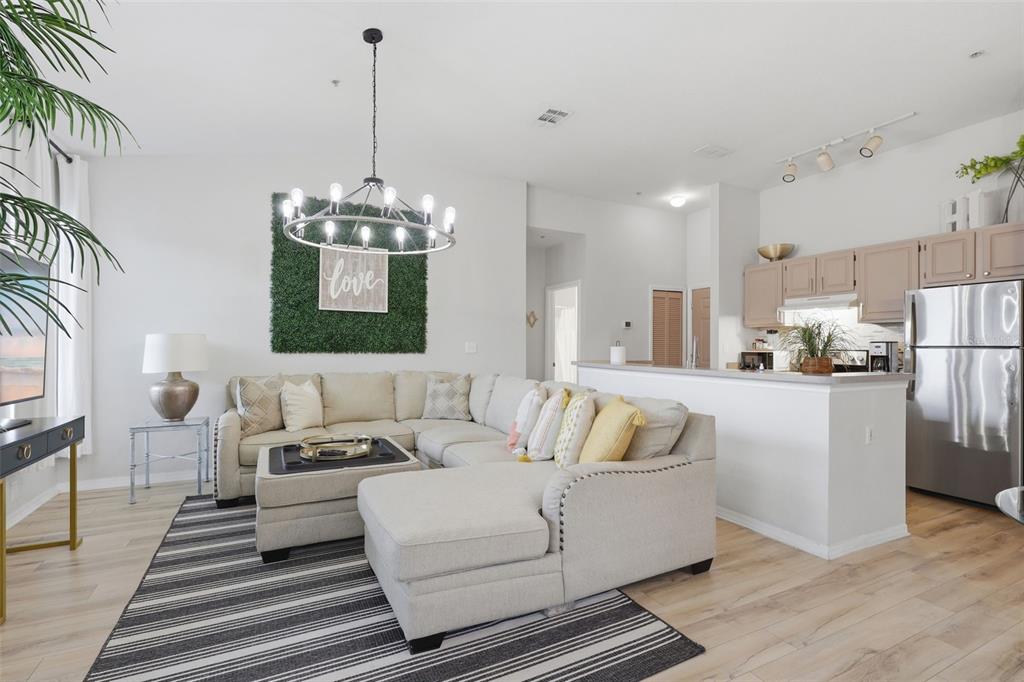 A living room with a sectional sofa, a chandelier, and an open kitchen with cabinets — 8807 DUNES COURT UNIT 308, KISSIMMEE, FL