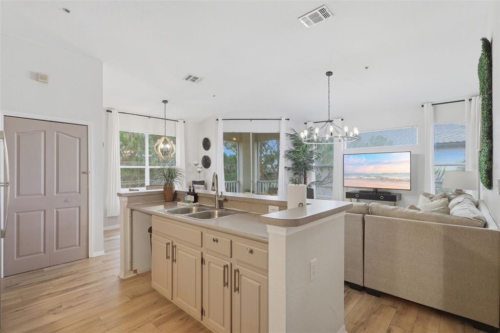 A kitchen with light-colored cabinets and a peninsula overlooks a living room with a sofa — 8807 DUNES COURT UNIT 308, KISSIMMEE, FL
