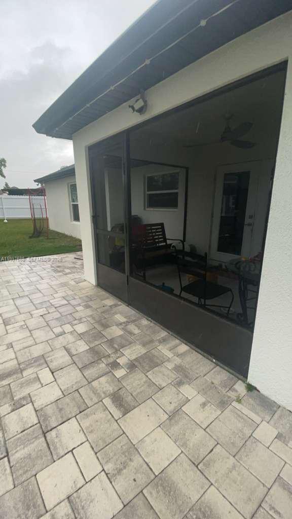 A paved patio leads to a screened-in porch with a ceiling fan and outdoor furniture — 5715 SW 128TH Pl, Ocala FL 34473, OCALA, FL