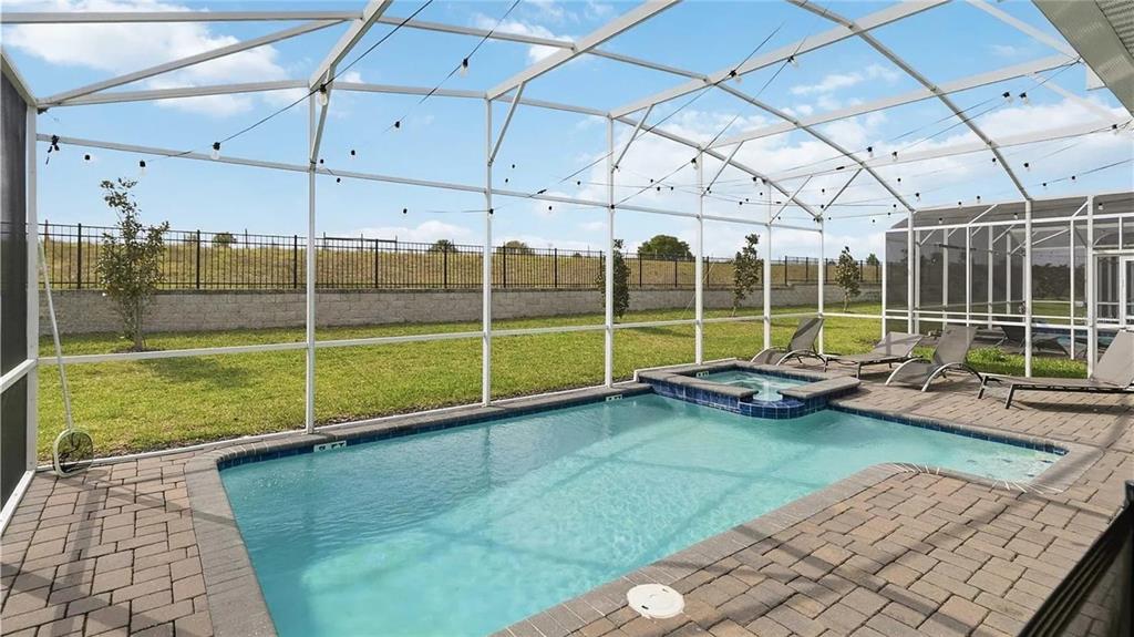A swimming pool and hot tub are enclosed within a screened lanai with paver decking — 9114 SOMMERSET HILLS DRIVE, DAVENPORT, FL