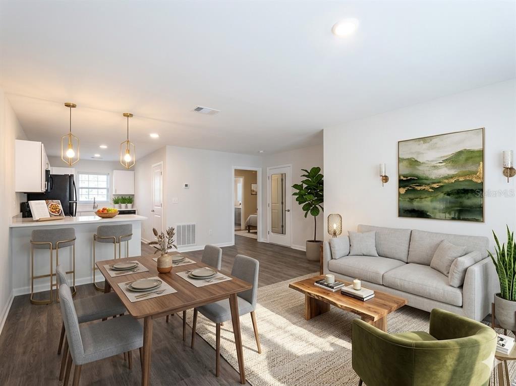 An open-concept living and dining area features a kitchen island, wood flooring, and neutral furniture — 9474 N CAMEL DRIVE, DUNNELLON, FL