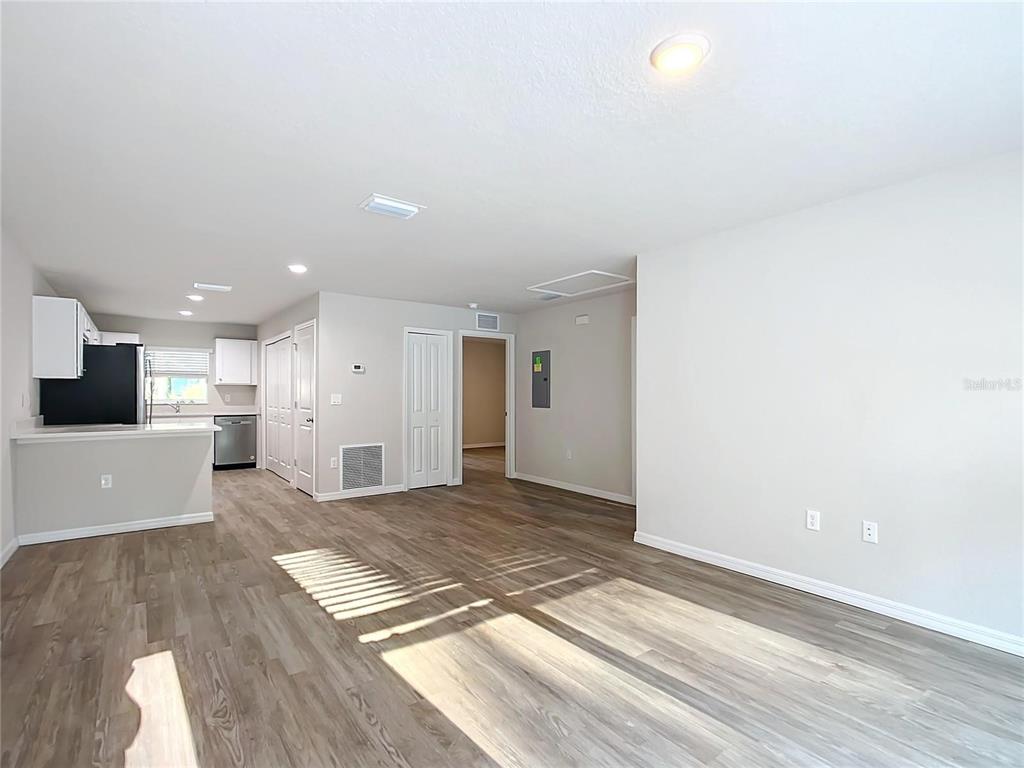 A living area with wood-look flooring flows into an open kitchen with white cabinets — 9474 N CAMEL DRIVE, DUNNELLON, FL
