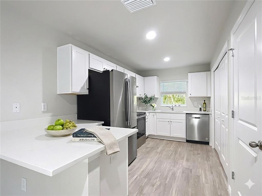 A kitchen with white cabinets, stainless steel appliances, and a white countertop peninsula — 9474 N CAMEL DRIVE, DUNNELLON, FL
