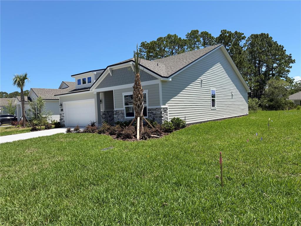 A single-story house with light siding, stone accents, and a two-car garage — 32 PERSEUS AVENUE, FLAGLER BEACH, FL