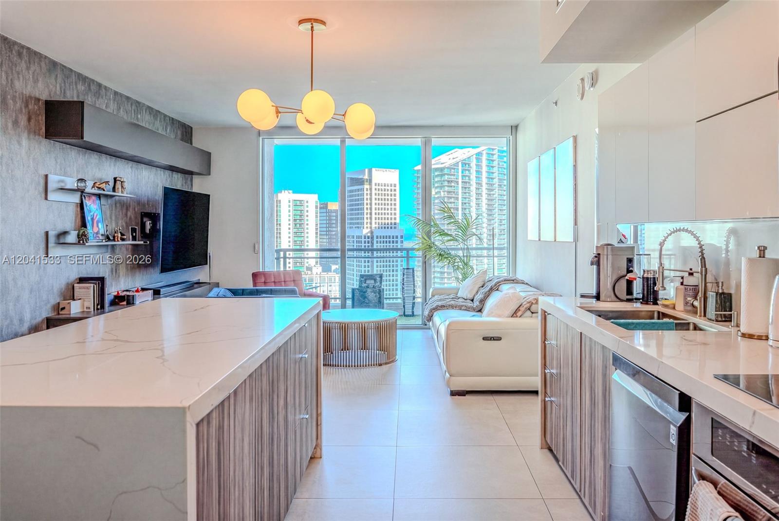 A modern kitchen and living area features a marble island, white cabinetry, and floor-to-ceiling windows — 90 SW 3rd St # 3703, Miami FL 33130, MIAMI, FL