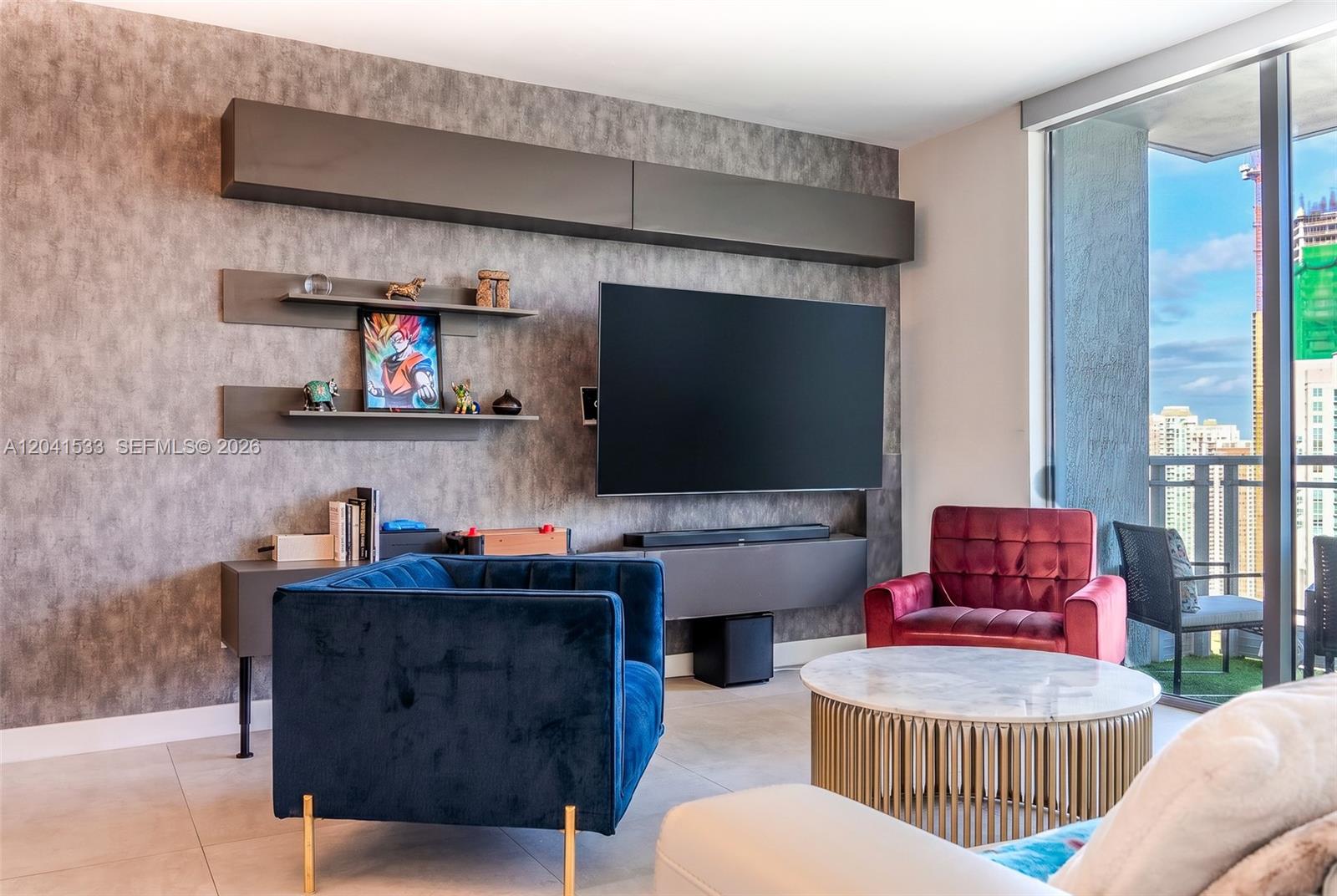 A modern living room features a textured accent wall, a wall-mounted television, and colorful armchairs — 90 SW 3rd St # 3703, Miami FL 33130, MIAMI, FL