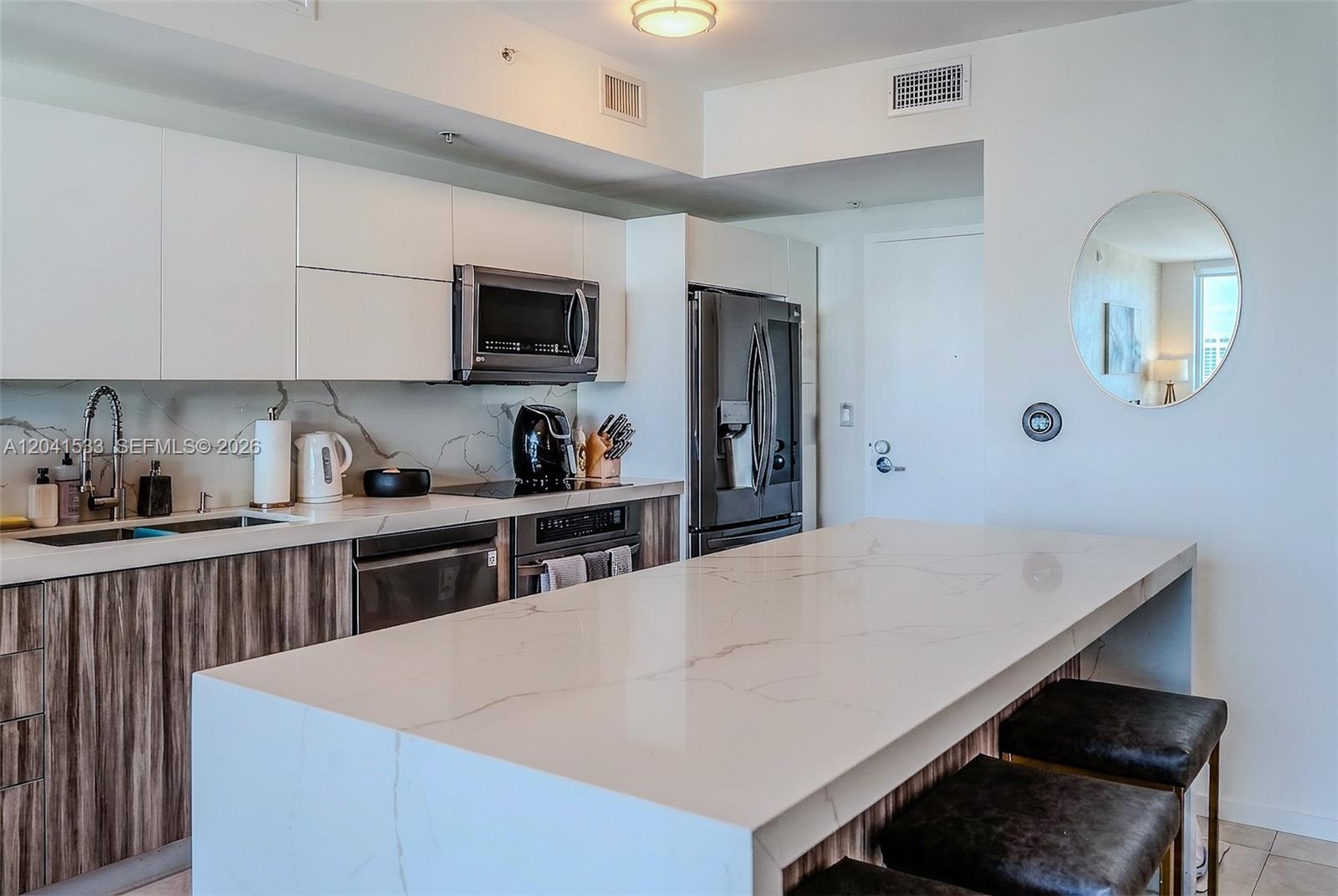 A modern kitchen features white cabinetry, a marble-patterned island, and dark wood-grain lower cabinets — 90 SW 3rd St # 3703, Miami FL 33130, MIAMI, FL