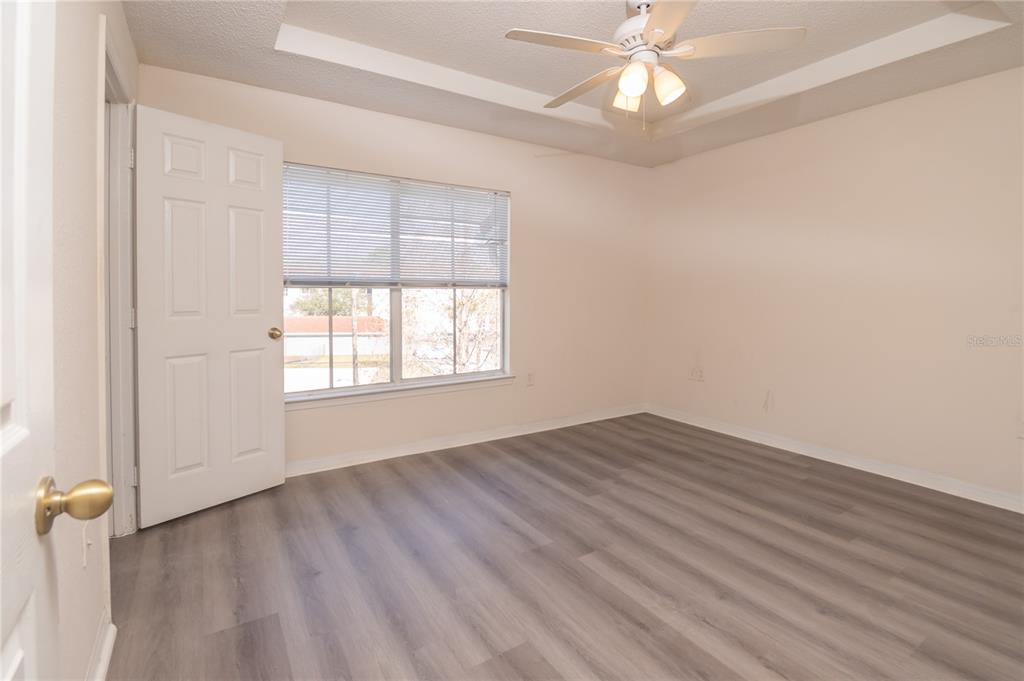 An empty bedroom features light-colored walls, a tray ceiling with a fan, and wood-look flooring — 18001 RICHMOND PLACE DRIVE UNIT 834, TAMPA, FL