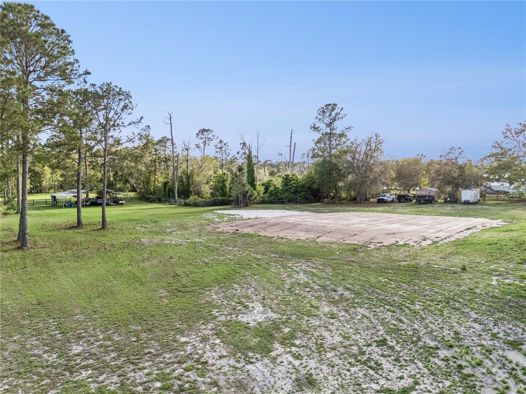 A large, grassy lot features a cleared rectangular dirt pad and several scattered trees — 110 WILD HORSE RUN, DELTONA, FL