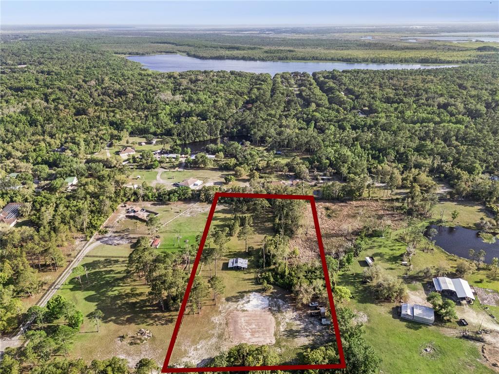 An aerial view shows a large, rectangular plot of land with a house and trees — 110 WILD HORSE RUN, DELTONA, FL