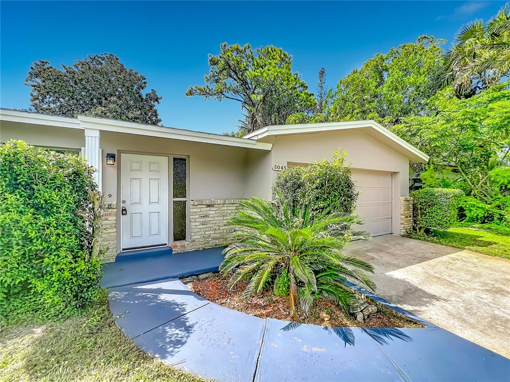 A single-story house with a white front door, brick accents, and a paved driveway — 3045 AVON LANE, TITUSVILLE, FL