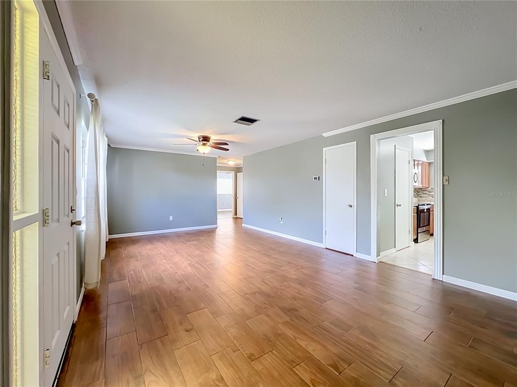 A living room with wood-look tile flooring, light green walls, and a ceiling fan — 3045 AVON LANE, TITUSVILLE, FL