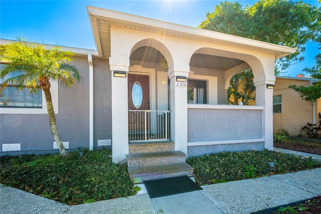 A front view of a house with a covered porch, stone steps, and a palm tree — 2300 37TH AVENUE N, ST PETERSBURG, FL