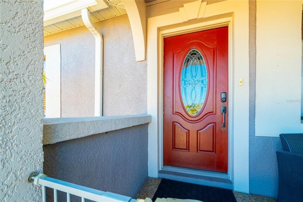 A red front door with an oval glass insert sits on a covered porch — 2300 37TH AVENUE N, ST PETERSBURG, FL