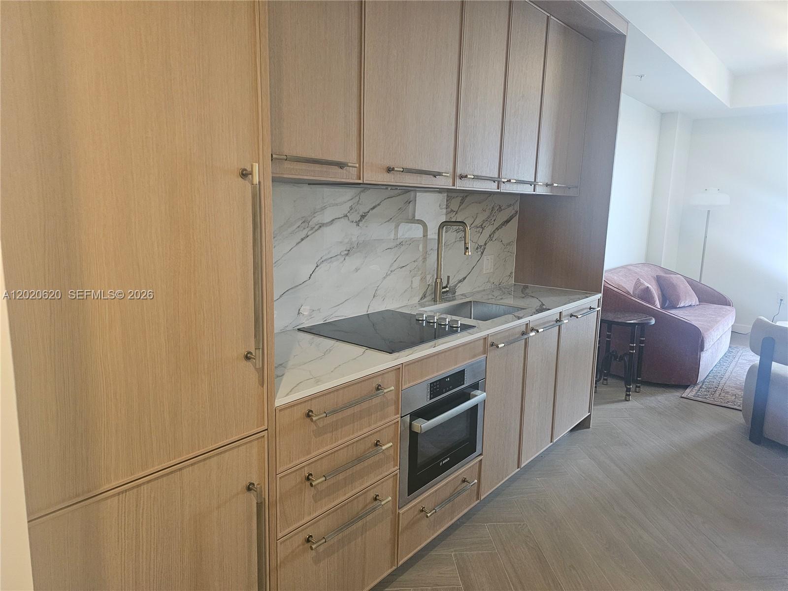 A modern kitchen features light wood cabinets, marble-patterned countertops, and a built-in oven — 2700 NW 2nd Ave # 610, Miami FL 33127, MIAMI, FL