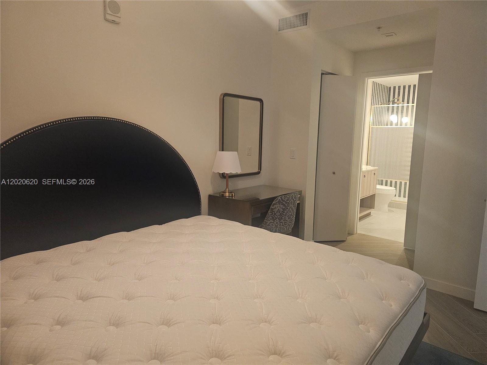 A bedroom features a tufted mattress, a dark headboard, a vanity, and an attached bathroom — 2700 NW 2nd Ave # 610, Miami FL 33127, MIAMI, FL
