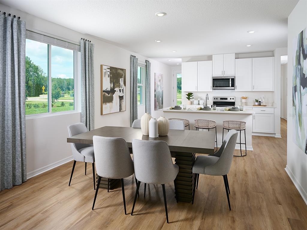 A dining area with a wooden table and chairs opens into a kitchen with white cabinets — 13403 SHELLMORE AVENUE, PALMETTO, FL