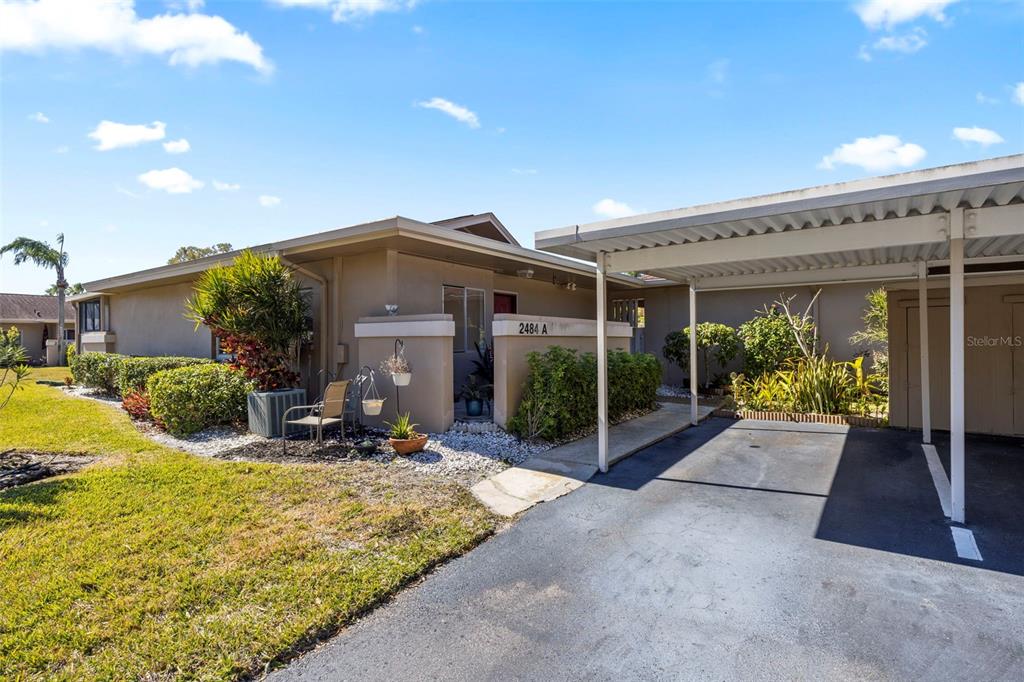 A single-story residence features a tan exterior, a covered carport, and a landscaped front yard — 2484 LAURELWOOD DRIVE UNIT A, CLEARWATER, FL