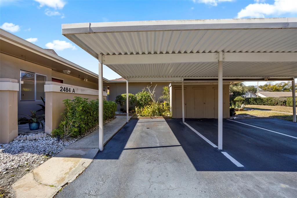 A covered carport with a concrete driveway sits beside a building with a numbered entrance — 2484 LAURELWOOD DRIVE UNIT A, CLEARWATER, FL