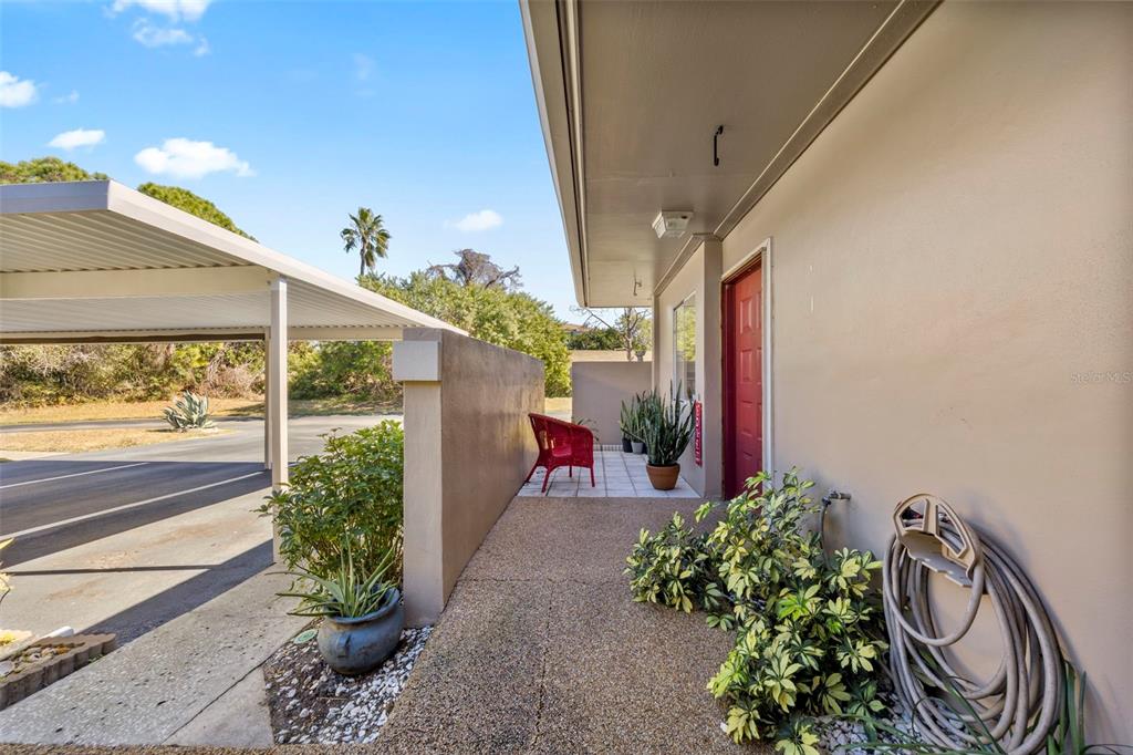 An exterior view of a home entrance with a carport, walkway, and red door — 2484 LAURELWOOD DRIVE UNIT A, CLEARWATER, FL