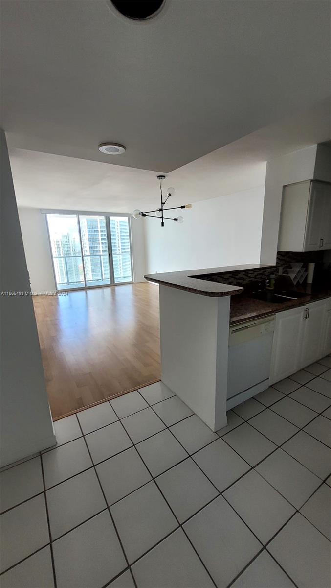 A kitchen with white cabinets and tile flooring overlooks a living area with wood floors — 1155 Brickell Bay Dr # 2805, Miami FL 33131, MIAMI, FL