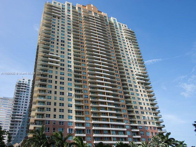 A tall, multi-story residential apartment building stands against a clear blue sky — 1155 Brickell Bay Dr # 2805, Miami FL 33131, MIAMI, FL