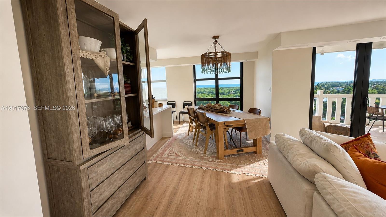 A dining area features a wooden table, a glass-front cabinet, and a view of trees — 1121 Crandon Blvd # E708, Key Biscayne FL 33149, KEY BISCAYNE, FL