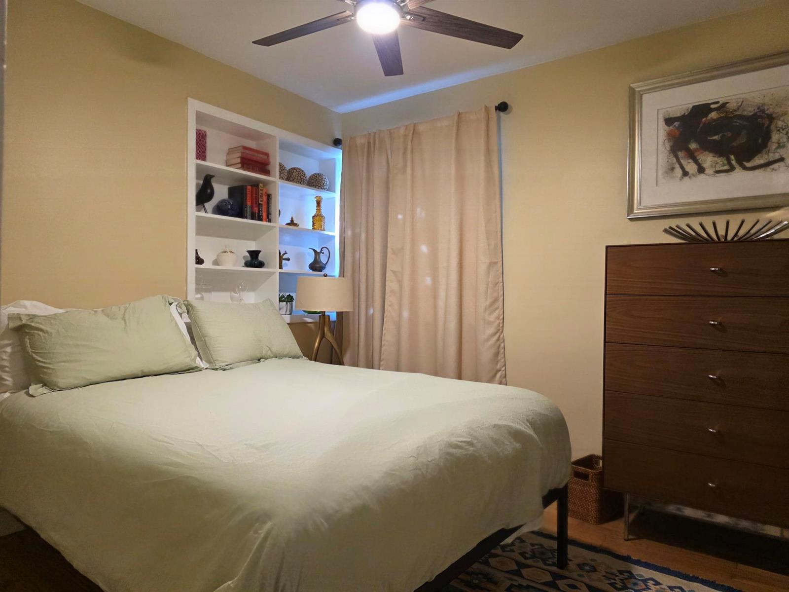 A bedroom features a bed with light green bedding, built-in shelving, and a wooden dresser — 1118 N K Street, FL 33460, FL
