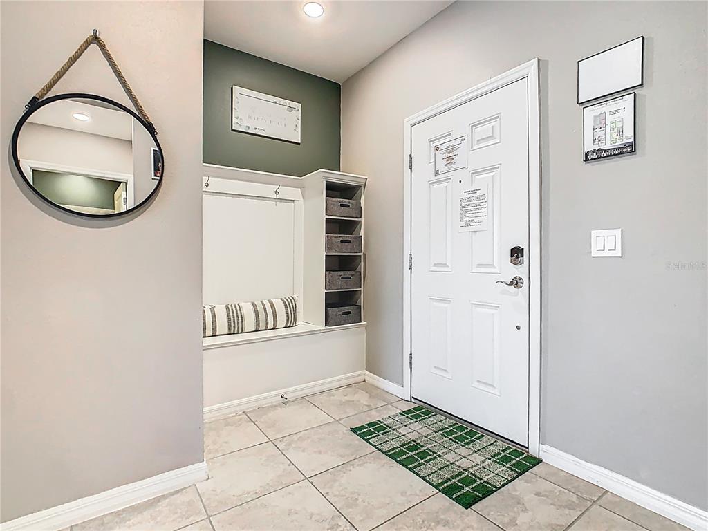 An entryway features a built-in bench, storage cubbies, a round mirror, and a tiled floor — 967 PARADISE DRIVE, DAVENPORT, FL