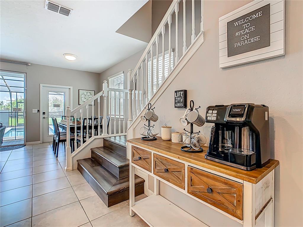 A coffee station sits on a wooden console table beside a staircase in a home — 967 PARADISE DRIVE, DAVENPORT, FL