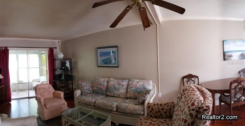 A living room features a floral sofa, a pink armchair, and a dining area — 2047 CANAL DRIVE UNIT L6, BRADENTON, FL